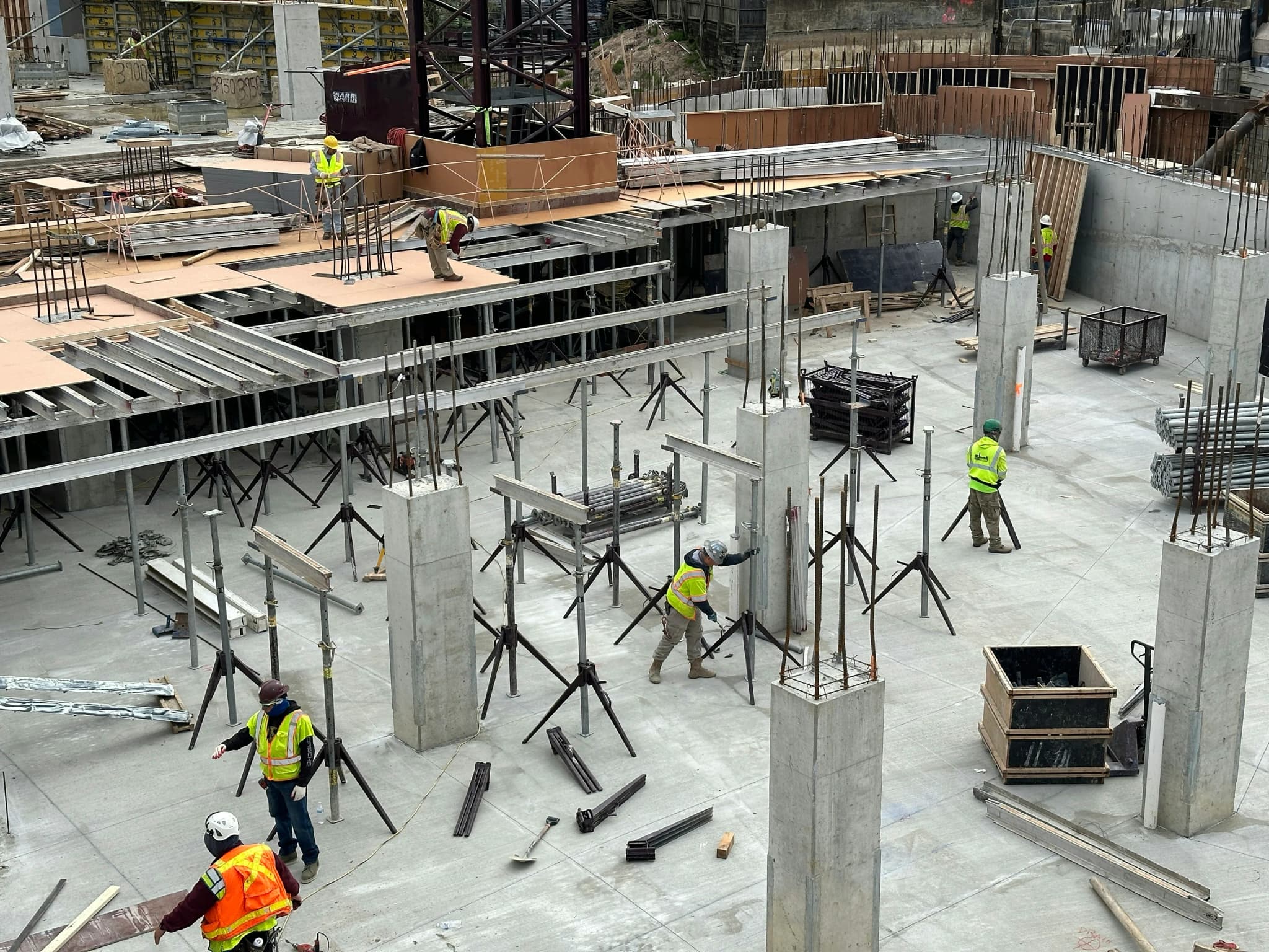 A crew working across a concrete deck among shoring posts and stripped columns