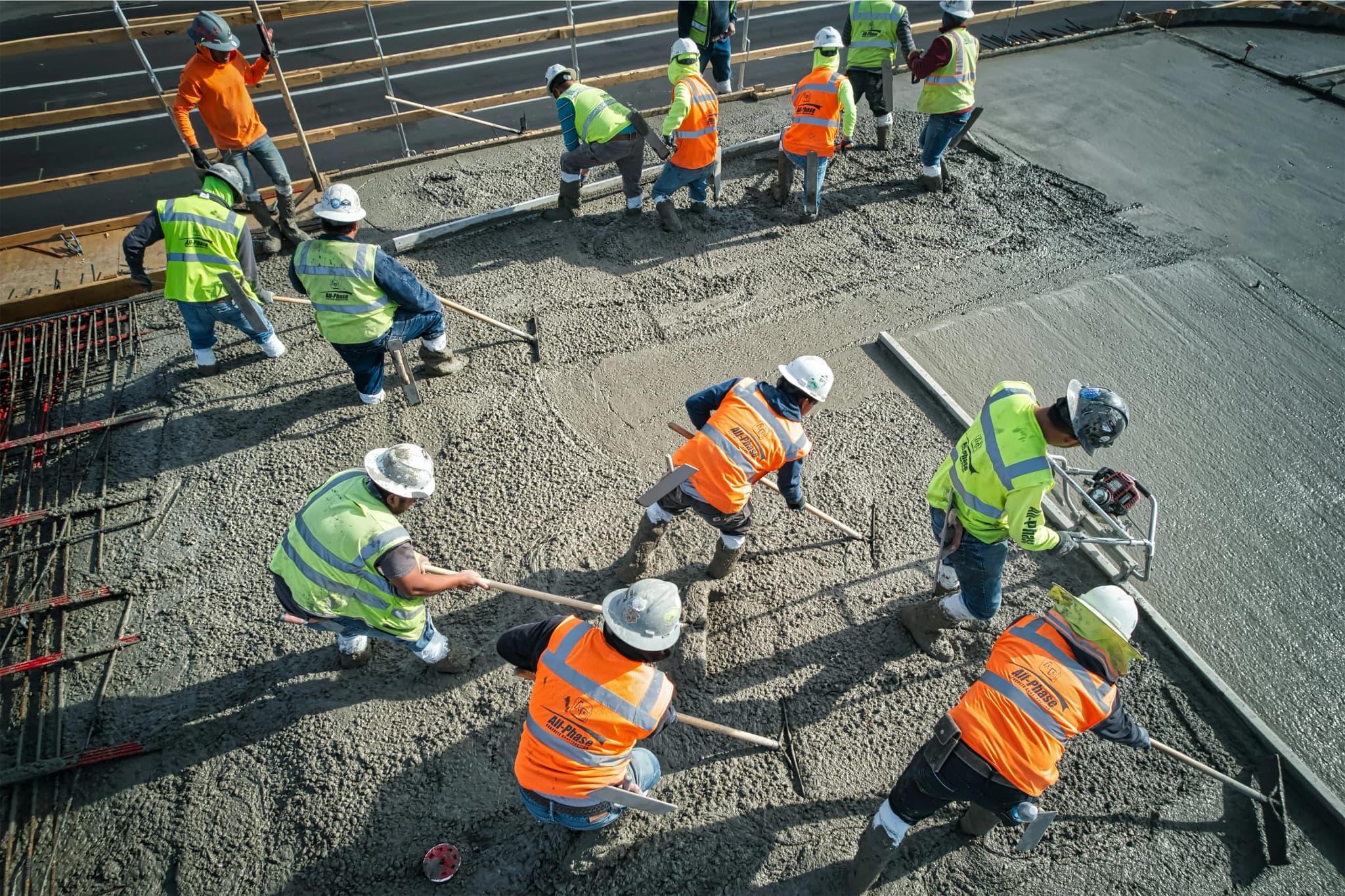 A crew screeding and floating a fresh concrete pour across a deck