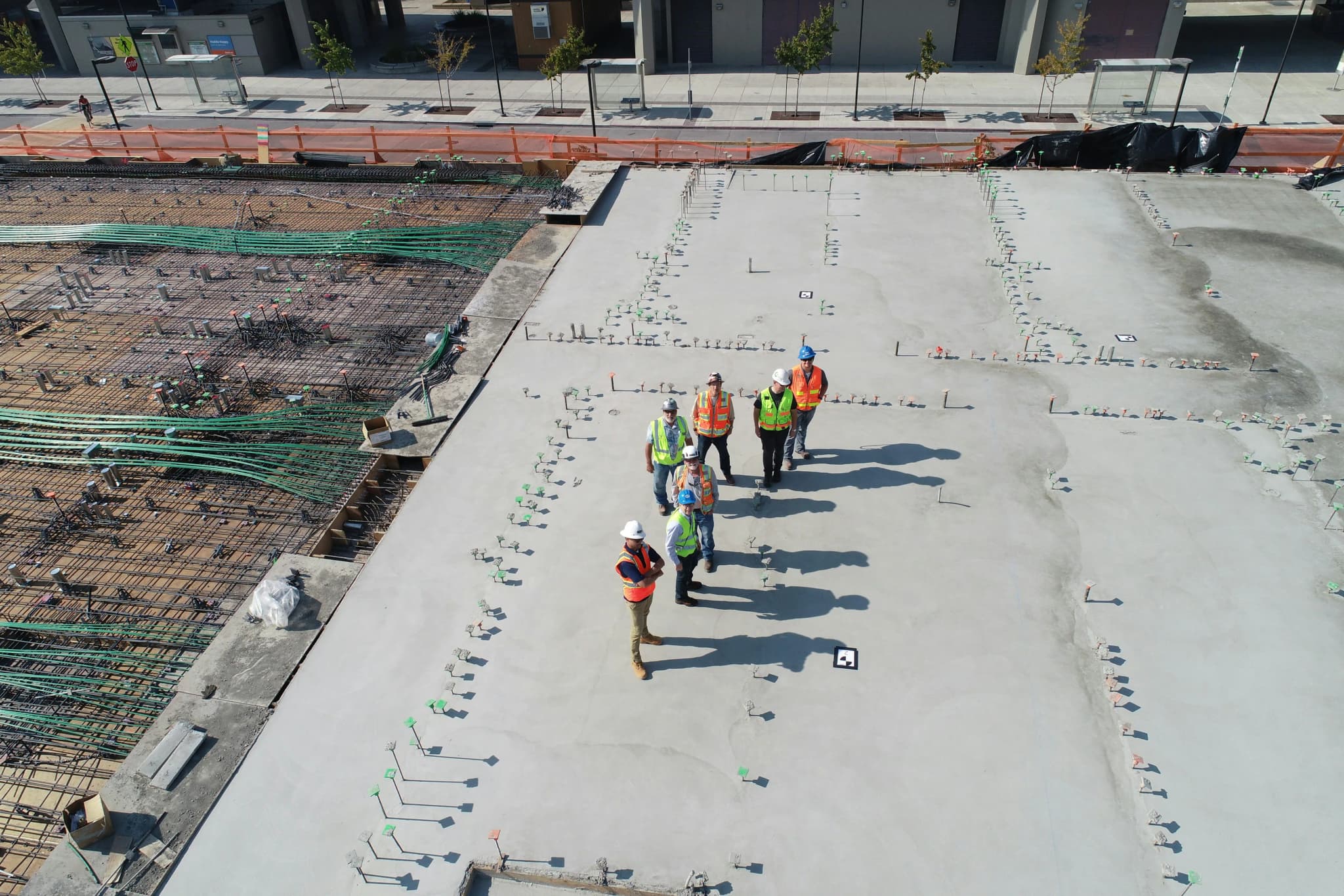 A crew gathered on a freshly poured concrete deck, seen from above