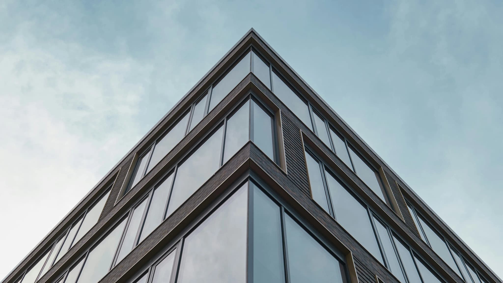 The glazed corner of a finished office building against a pale sky
