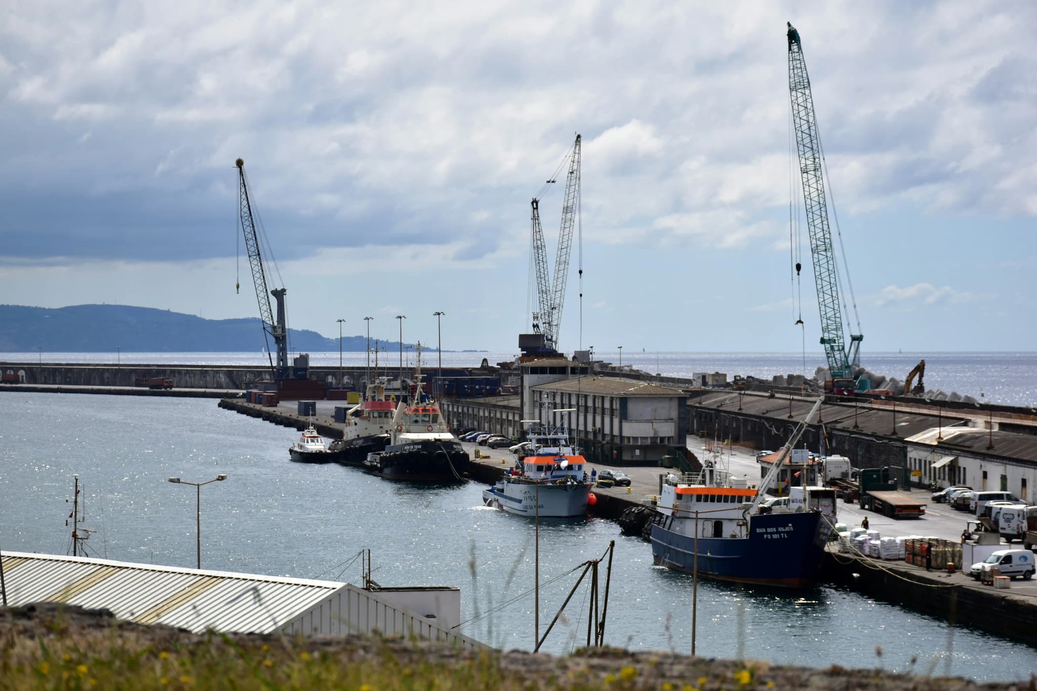 Crawler cranes and fishing boats at a working harbour on a cold coast