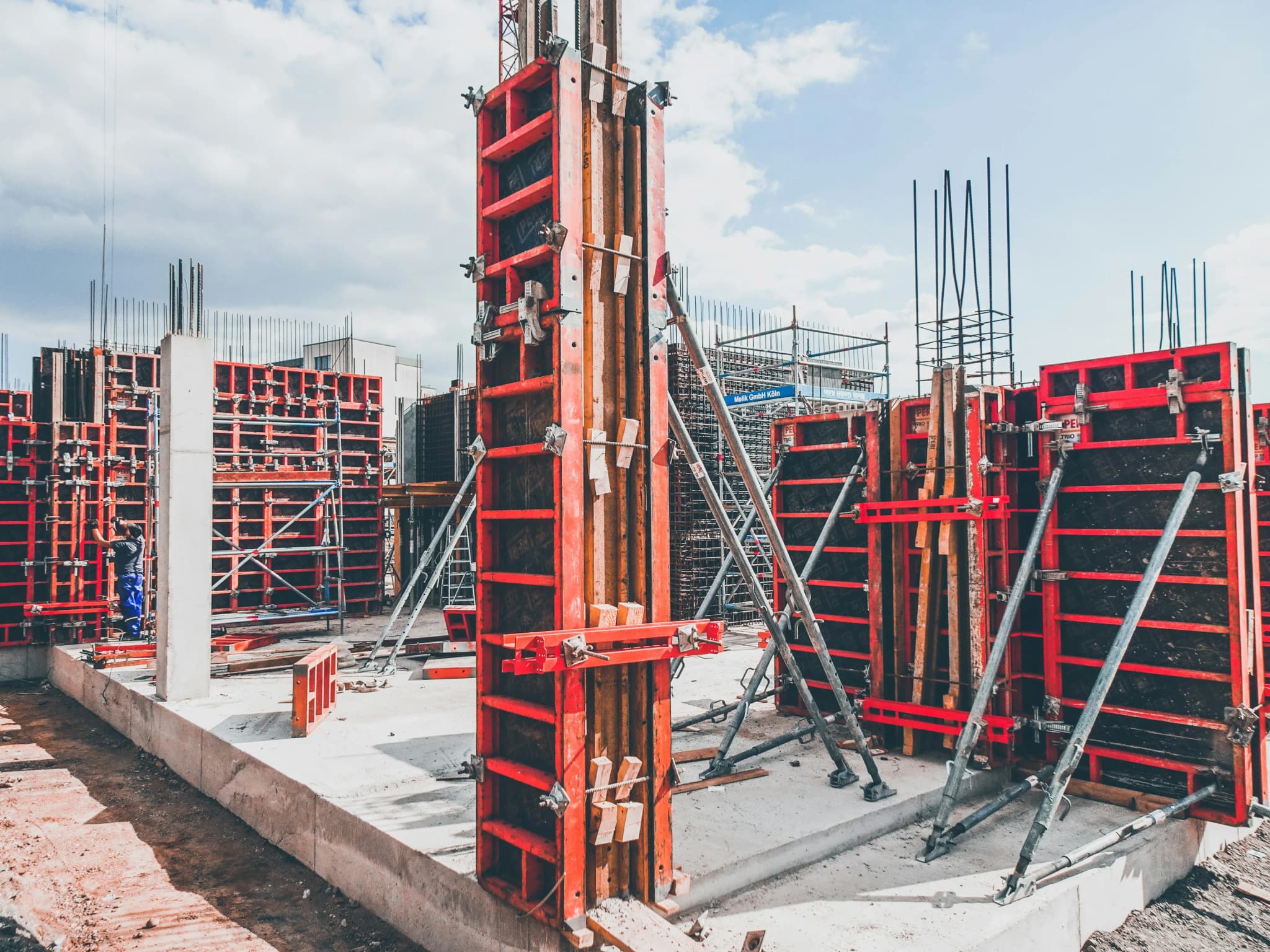 Red wall formwork panels braced upright and ready for a concrete pour